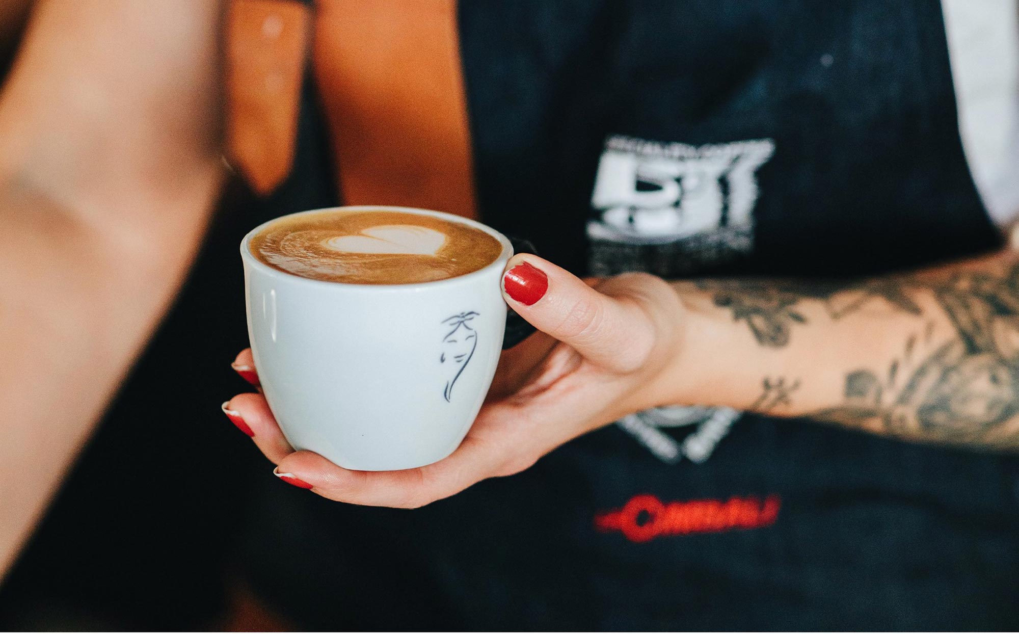 Kvinna på ett café som håller i en cappuccino